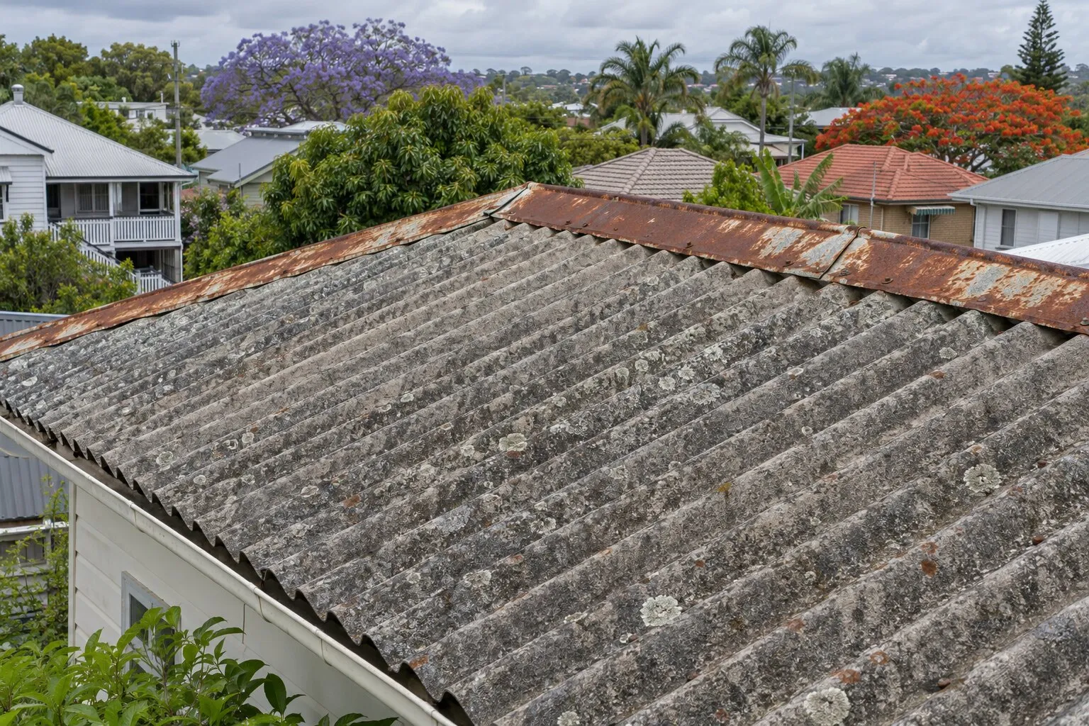 Asbestos roof sheets, Brisbane: weathered grey corrugated fibro roof with lichen and rusted ridge capping