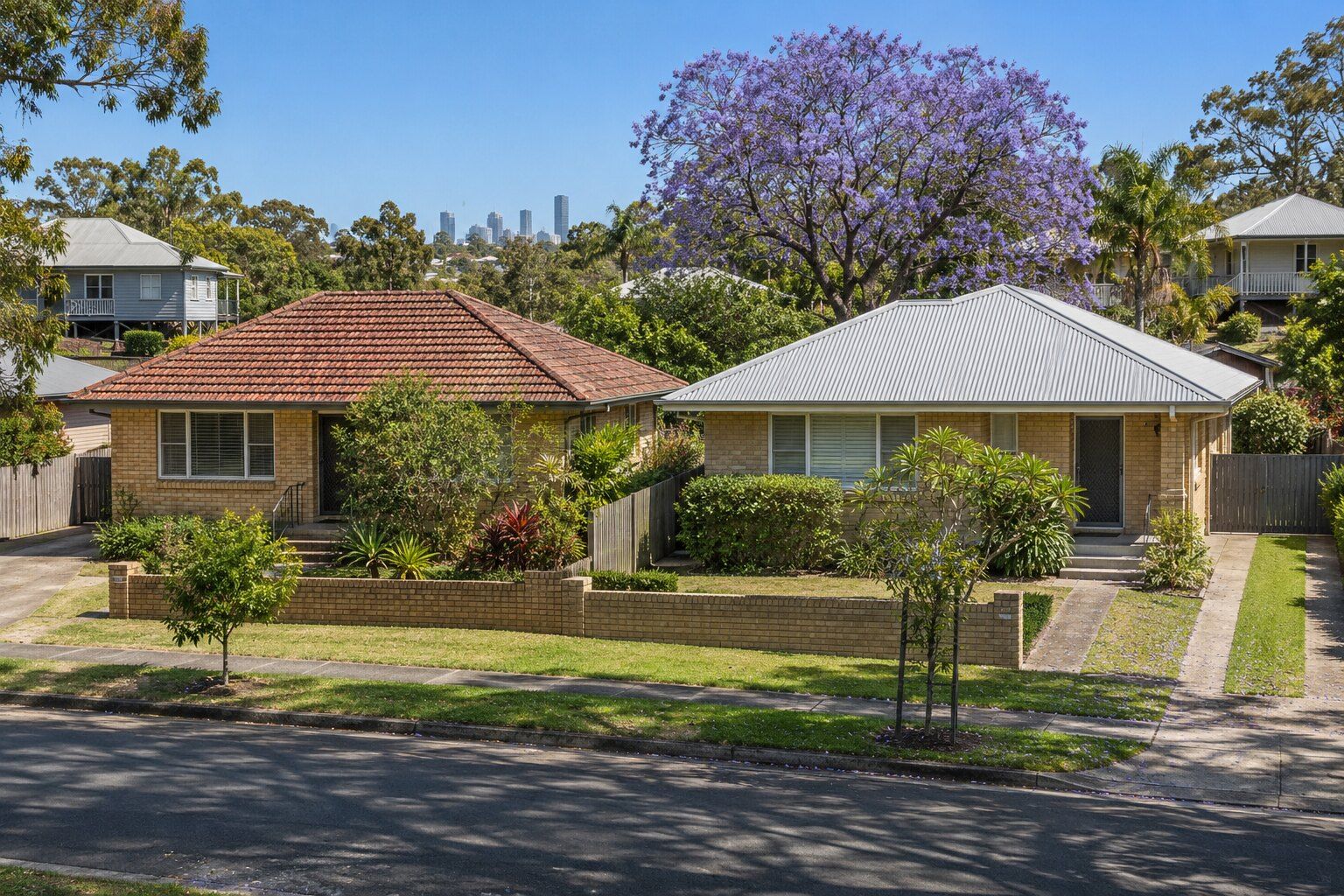 Colorbond vs tile roof, Brisbane: a terracotta tile roof beside a new pale grey Colorbond roof on neighbouring brick houses